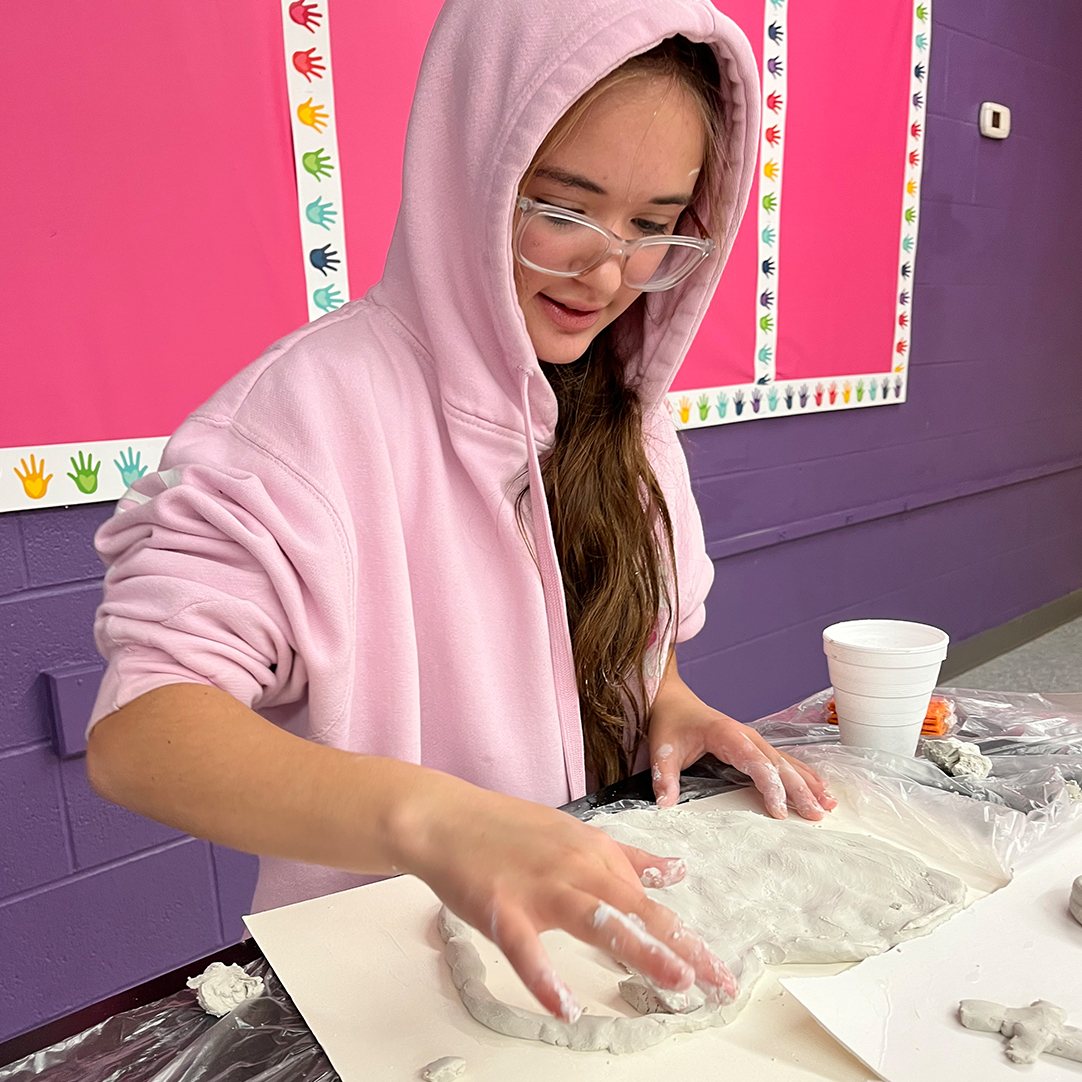 A girl engaged in a craft involving clay.